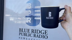 a hand holding up a BPR-branded mug in front of the station 