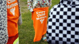 A Red Cloud Indian School student holds an orange T-shirt at an assembly for Orange Shirt Day on Sept. 30, 2021, in Pine Ridge, S.D. Students and teachers wore orange in solidarity with Indigenous children of past generations who suffered cultural loss, family separation and sometimes abuse and neglect while compelled to attend hundreds of residential schools that once dotted the map across the United States and Canada from the late 19th to the mid-20th centuries.