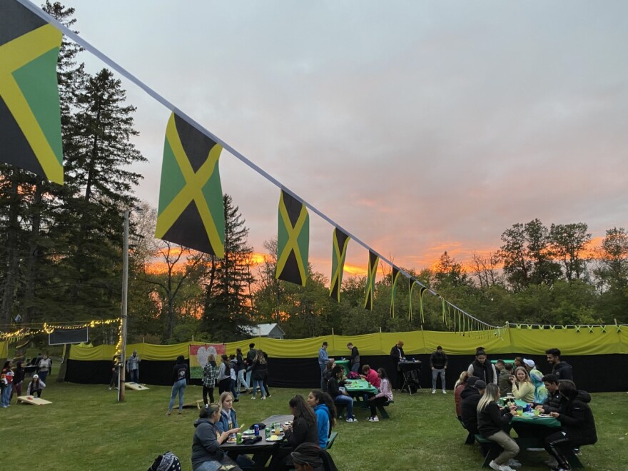 Students eating at picnic tables under strings of tiny Jamaican flags 