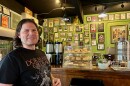 A man stands in front of a counter displaying pastries and coffee. 