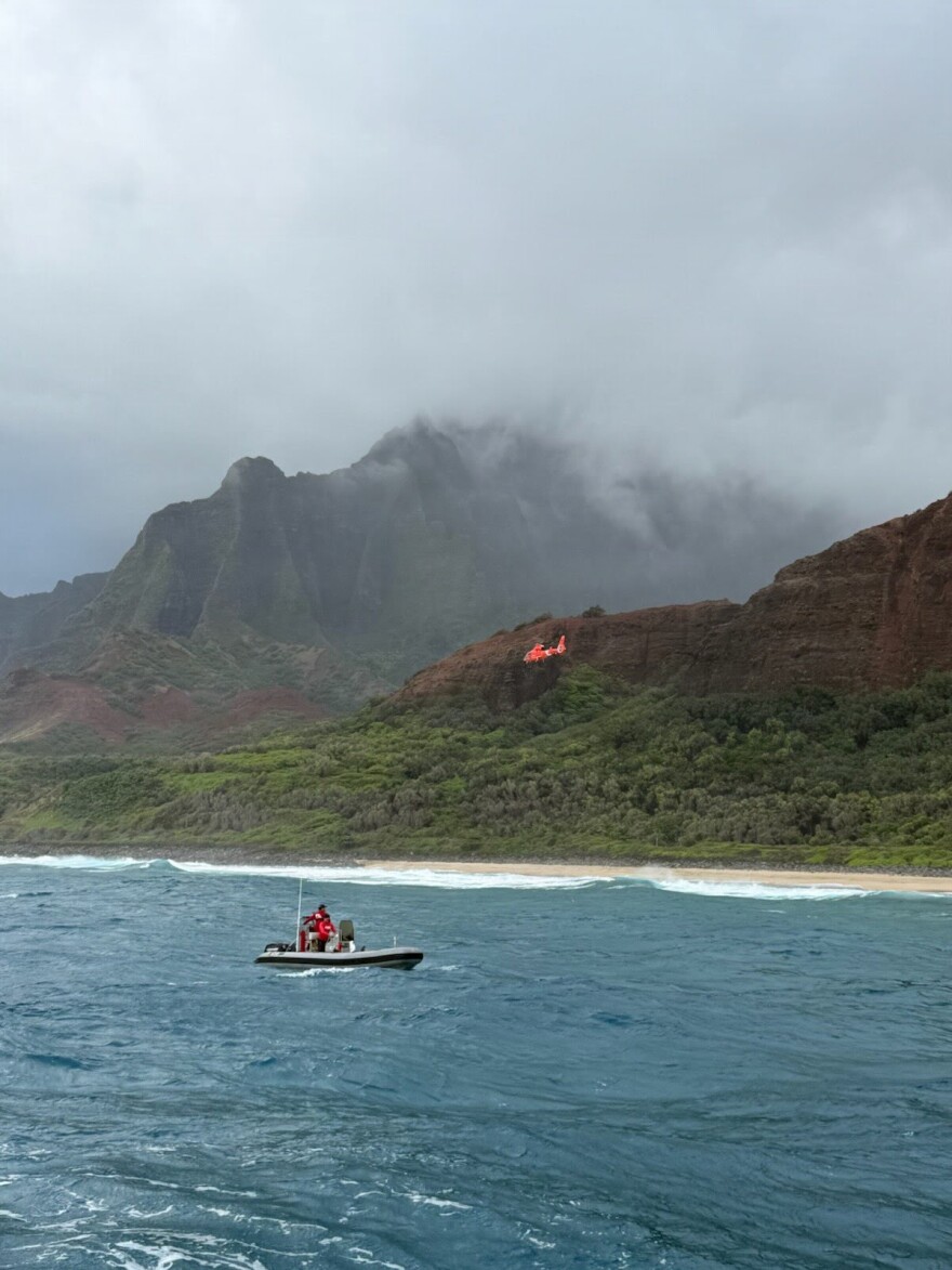 A Coast Guard Air Station Barbers Point MH-65 Dolphin helicopter crew and a Kauaʻi Ocean Safety Bureau boat crew traverse the shoreline near Kalalau Beach on Kauaʻi, March 26, 2026. (U.S. Coast Guard photo. Courtesy Station Kauaʻi)