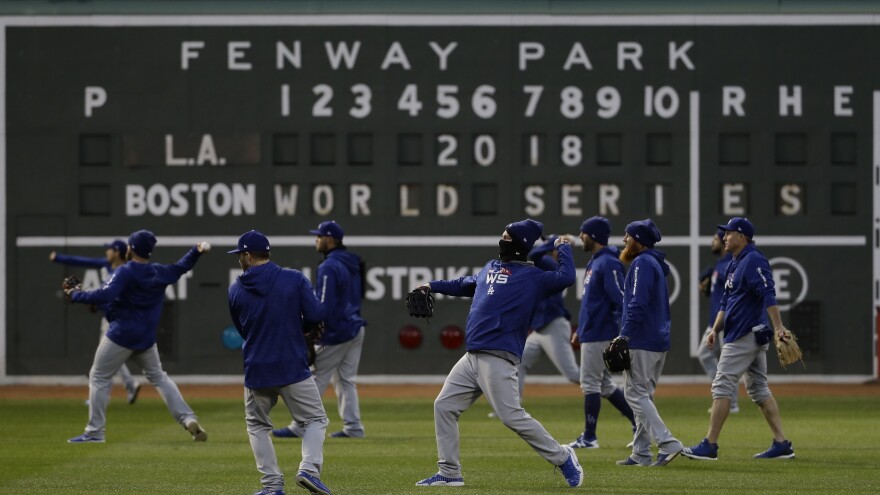 Bundled-up members of the Los Angeles Dodgers practice Tuesday at Fenway Park in Boston for Game 1 of the World Series against the Boston Red Sox. Temperatures are expected to drop into the low 40s tonight, and thunderstorms are possible.