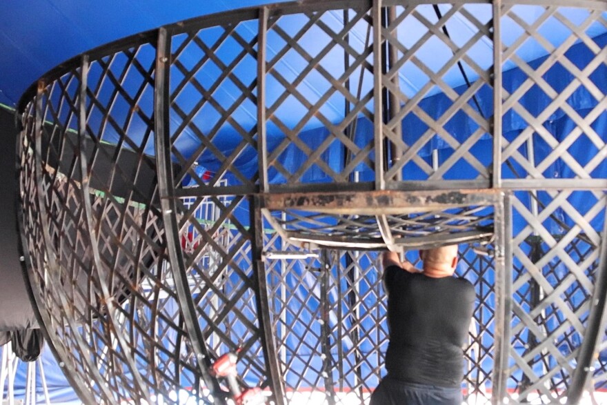 Workers put together the steel cage for the performance a few days before the fair starts.