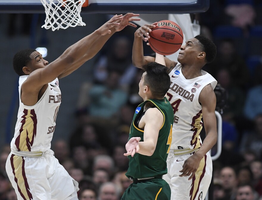 Florida State's Devin Vassell, right, blocks a shot attempt by Vermont's Robin Duncan, center, as Florida State's David Nichols, left, defends during the second half of a first round men's college basketball game in the NCAA tournament, Thursday, March 21, 2019, in Hartford, Conn.