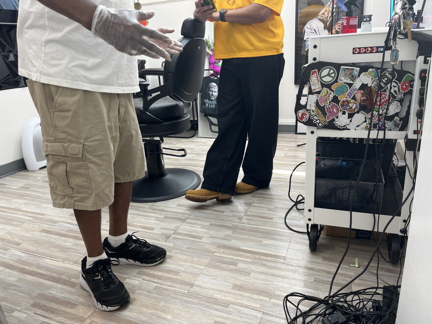 Felix, 67, wears a pair of gloves at a barber shop on Elizabeth Avenue near uptown.