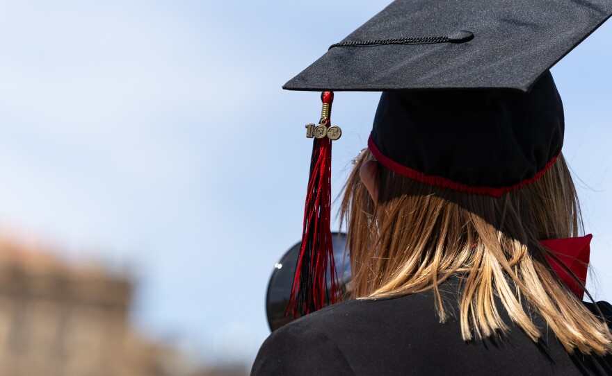 A person in a Texas Tech cap and gown holds a megaphone.