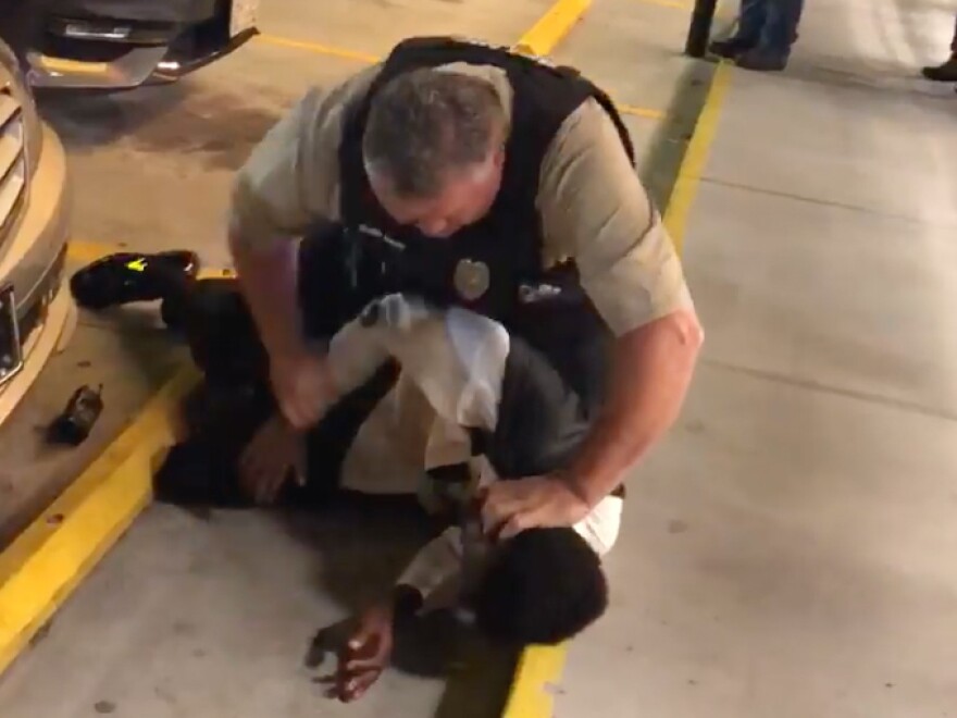 The video shows a white police officer choking a young tuxedo-clad man who is African-American, pushing him against a storefront and then slamming him to the ground outside a North Carolina Waffle House.