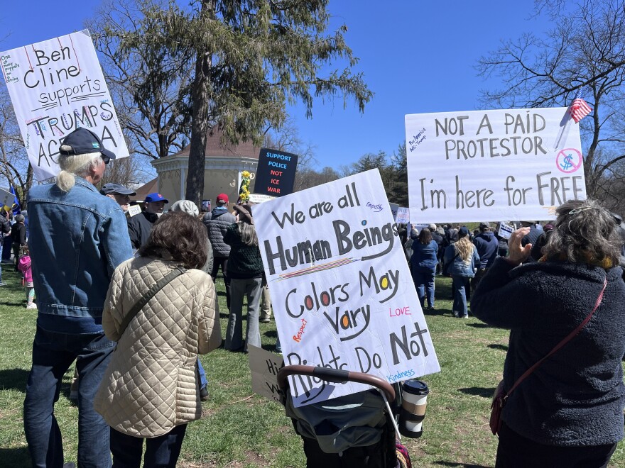 Rally-goers hold up protest signs in front of the bandstand at Gypsy Hill Park as they listen to speakers and musical performances.