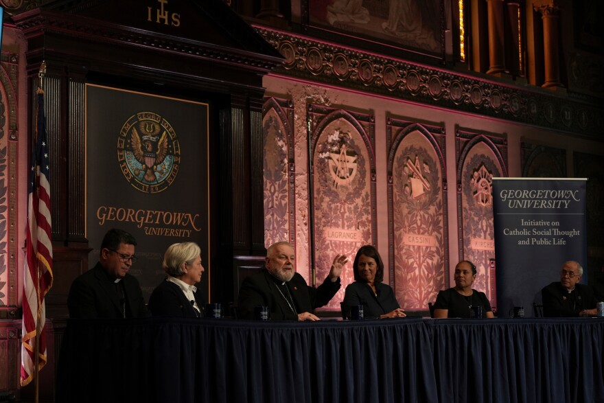 FILE - The archbishop of Miami, Thomas Wenski, raises his hand while addressing a crowd during a panel on immigration at Georgetown University in Washington, Thursday, Sept. 11, 2025.