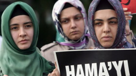 Members of a pro-Islamic human rights group and Syrians living in Turkey gather, one holding a placard that reads, "we did not forget Hama" as they stage a protest against the Syrian regime and its leader Bashar Assad during a protest outside the Syrian embassy in Ankara, Turkey, Monday, Aug. 1, 2011.