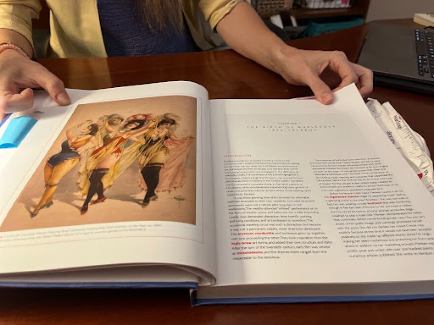 Chloe Edmondson flips through the “Costumes of Burlesque” book.