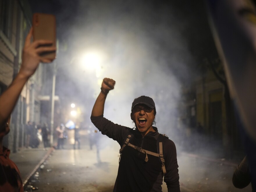 A supporter of Guatemalan President-elect Bernardo Arévalo celebrates that lawmakers voted for a Seed Movement member to be their new Congress president, Samuel Perez, as part of the process before Arévalo's swearing-in ceremony, outside the National Palace in Guatemala City, Sunday, Jan. 14, 2024.