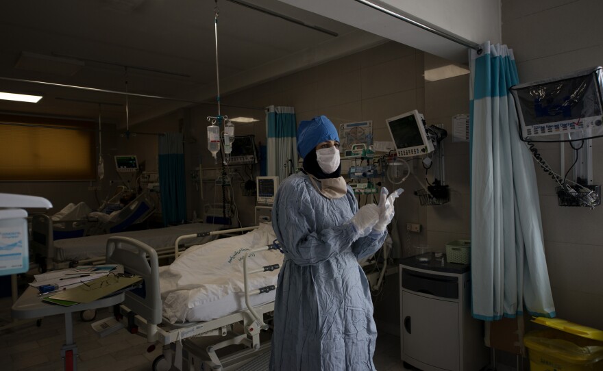 A nurse puts on gloves to visit a patient who is thought to have the coronavirus. Because of the enormous number of patients in the hospitals, the tests for the coronavirus might take several days. So all health care professionals have to assume that patients with symptoms are positive.