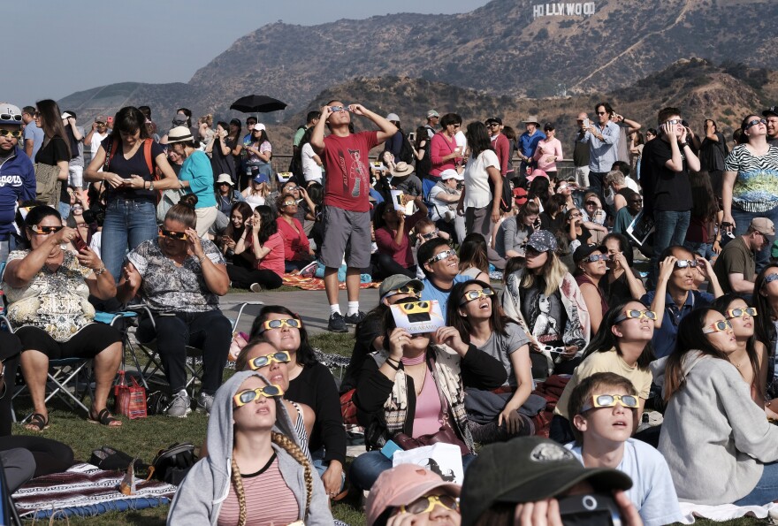 A crowd gathers in front of the Hollywood sign at the Griffith Observatory to watch the solar eclipse in Los Angeles on Monday, Aug. 21, 2017. (AP Photo/Richard Vogel)