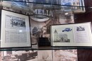 A lit glass case depicts a newspaper article, photographs and old meeting-minute books from the Village of Amelia.