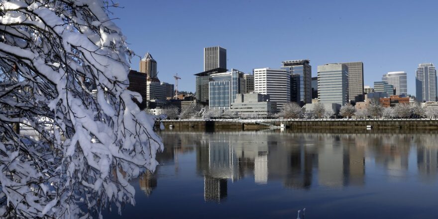 Snow and ice cling to tree limbs as downtown Portland, Ore., is reflected in the Willamette River under blue skies, Thursday, Jan. 12, 2017. (Don Ryan/AP)