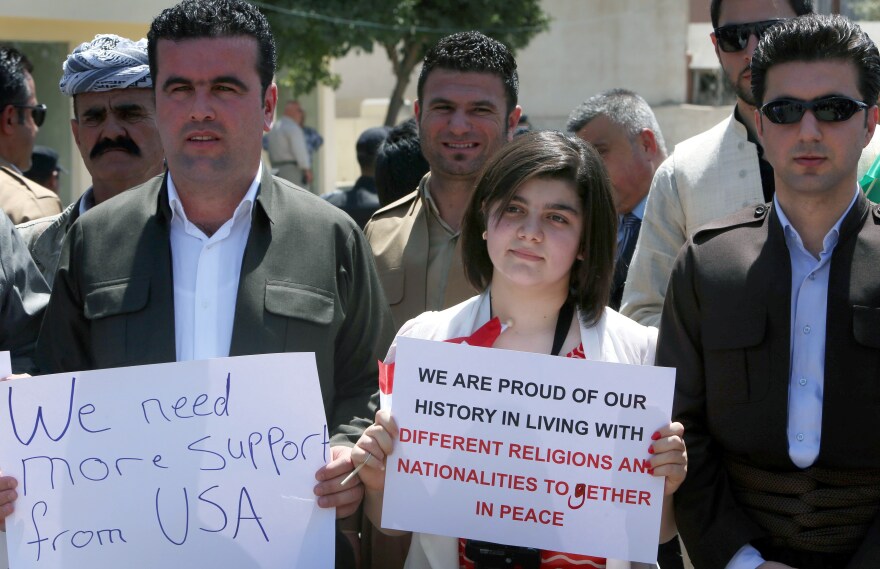 A group consisting mainly of Iraqi Christians hold signs during a rally in front of the U.S. consulate in Erbil, capital of the autonomous Kurdish region of northern Iraq, calling for more support and thanking the US. for air strikes aimed at halting the advance of Sunni Islamic State militants.