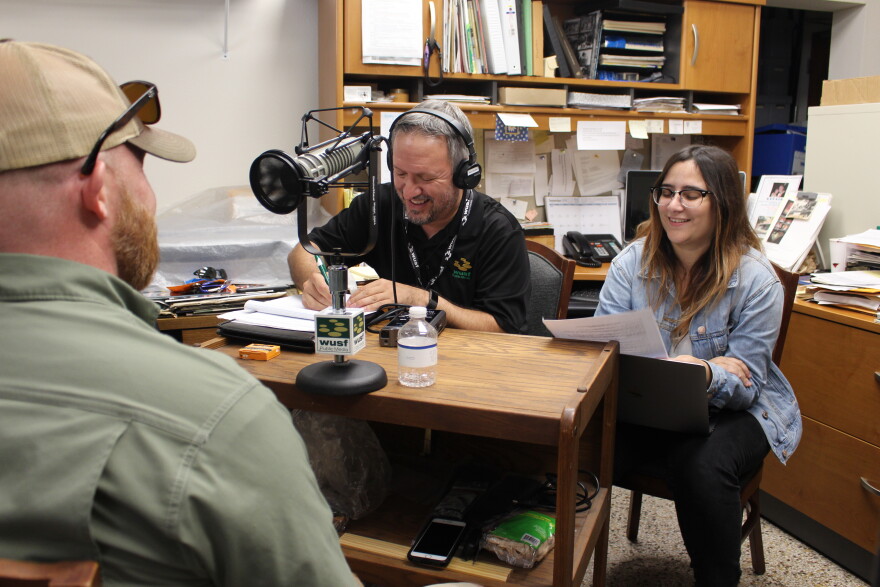 Johnson's Barbecue owner Owen Johnson, left, talks to WUSF's Mark Schreiner and USF student journalist Yara Zayas.