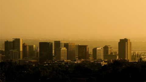 The Salt Lake City skyline veiled in smoke. The air appears yellow as the sun sets. 