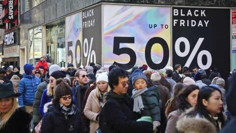 File - Crowds walk past a large store sign displaying a Black Friday discount in midtown Manhattan, Friday, Nov. 23, 2018, in New York. While Black Friday may no longer look like the crowd-filled, in-person mayhem that it was just decades ago — in large part due to the rising dependence on online shopping that was accelerated by the COVID-19 pandemic — the holiday sales event is still slated to attract millions of consumers. (AP Photo/Bebeto Matthews, File)