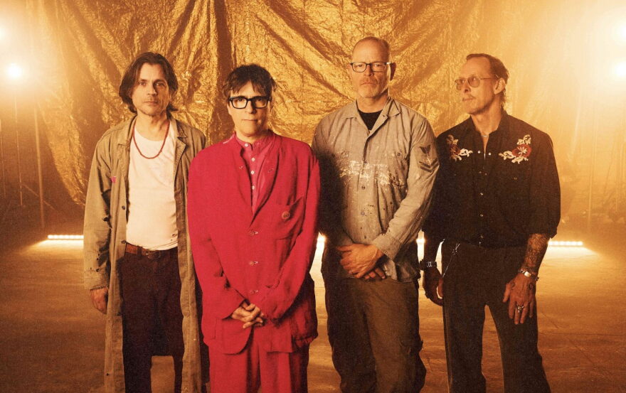 Group of four men stands together with glowing light behind them 