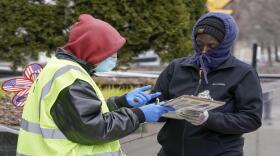 A worker helps voter outside the Frank P. Zeidler Municipal Building Monday March 30, 2020, in Milwaukee.