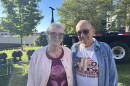 A man and woman stand together in a park. The man is wearing a 9/11 "Never Forget" shirt.