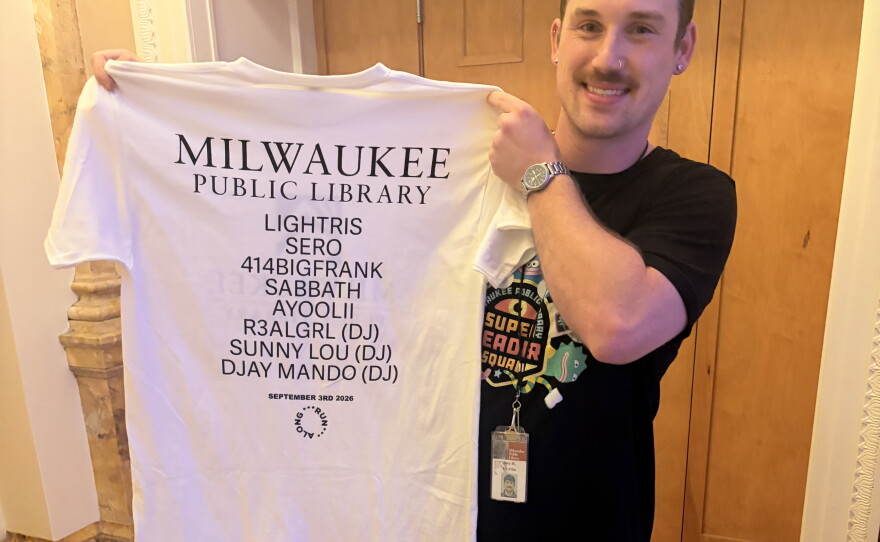 Joey McMahon, the research and policy coordinator at the Milwaukee Public Library, holds up the limited edition band tee created for The Library Show.