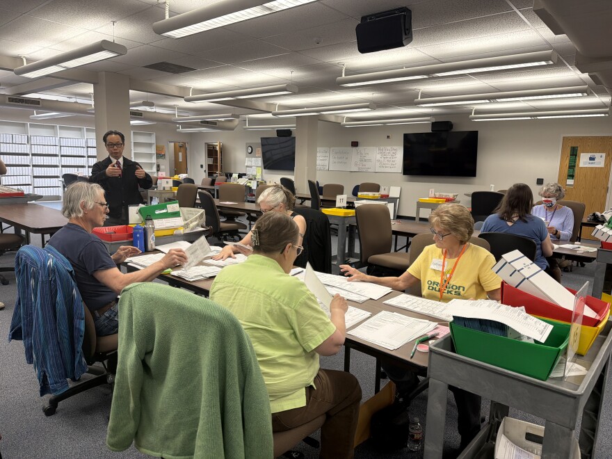 A group of Lane County Elections Office employees remove ballots from their envelopes and unfold them, preparing them to be scanned for vote counting, May 15, 2026.