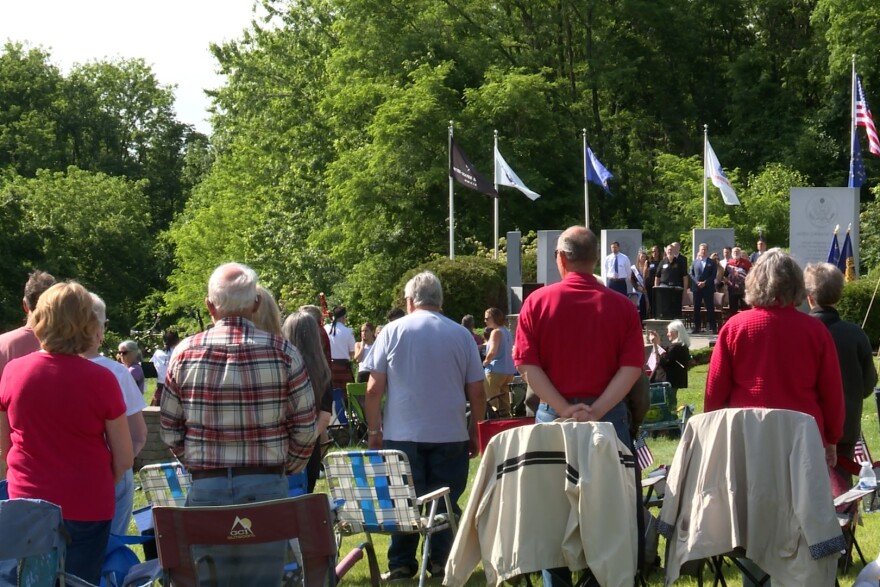 Adults standing and facing toward military flags