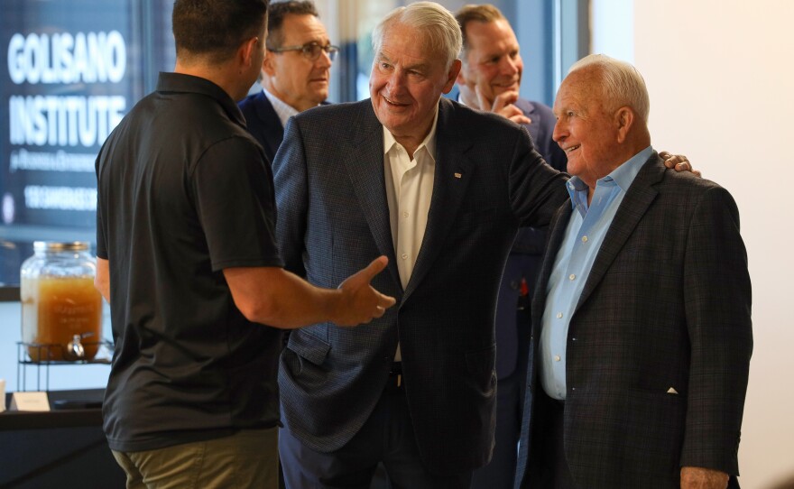 Philanthropist Tom Golisano and Phil Saunders, chairman of Saunders Management, talk with U.S. bobsled team member Frank Del Luca before Eastman Kodak Company announced its support of USA Bobsled/Skeleton ahead of the 2026 Winter Olympics, unveiling a new state-of-the-art bobsled in Kodak’s iconic yellow and red at the Golisano Institute for Business & Entrepreneurship. The historic 1956 bronze medal–winning “Tyler Sled,” designed and raced by Kodak engineers, was also on display.