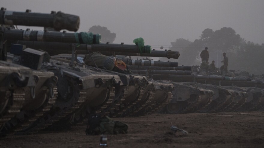 Israeli soldiers stand on top of a tank in a staging area at the Israeli-Gaza border in southern Israel, on Monday.