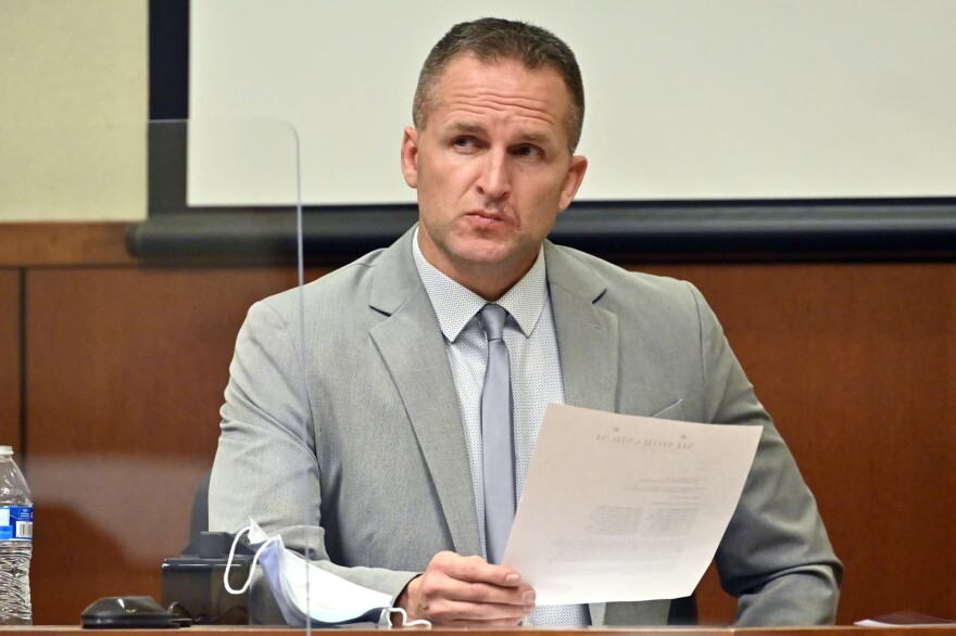 Former Louisville Police officer Brett Hankison examines a document as he answers questions from the prosecution, March 2, 2022, in Louisville.