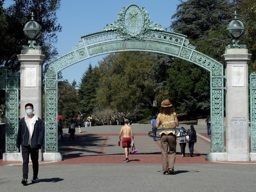A man wears a mask while walking past Sather Gate on the University of California at Berkeley campus in Berkeley, Calif., Wednesday, March 11, 2020.