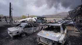 Burned vehicles sit near an oil storage facility struck by a U.S.-Israeli attack late Saturday as a thick plume of smoke rises in Tehran, Iran, Sunday, March 8, 2026. (Vahid Salemi/AP)