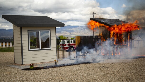During a recent demonstration burn at the National Interagency Fire Center, one poorly prepared shed-like structure burns to the ground while the other escapes undamaged.
