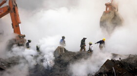 Firefighters make their way over the ruins of the World Trade Center through clouds of smoke at ground zero in New York.
