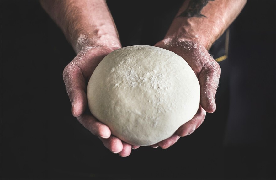Man holding dough in the palms of his hands.