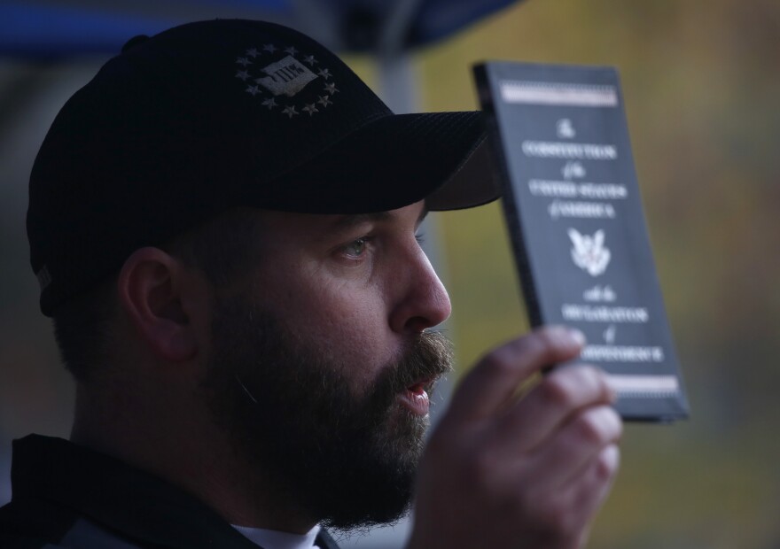 Matt Marshall, state leader of the Washington Three Percent, holds a copy of the U.S. Constitution during the United Against Hate rally.