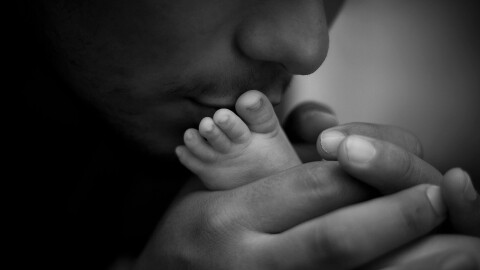 A father kisses his baby's foot.