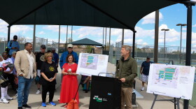 Albuquerque Mayor Tim Keller flanked by signs depicting the park renovations and city, county and state officials