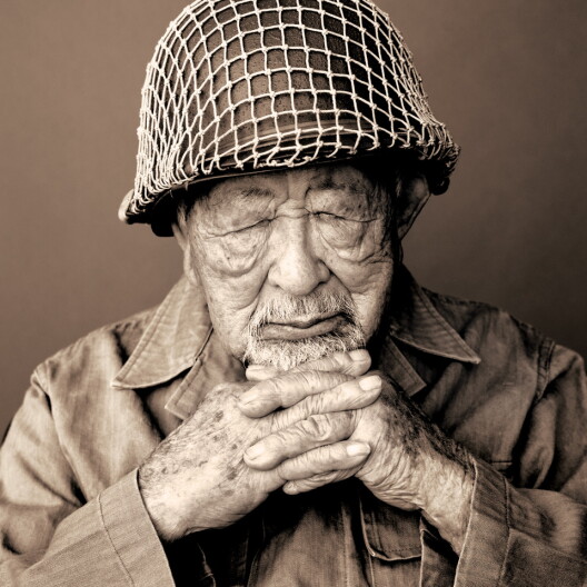 A World War II veteran sits with his eyes closed.