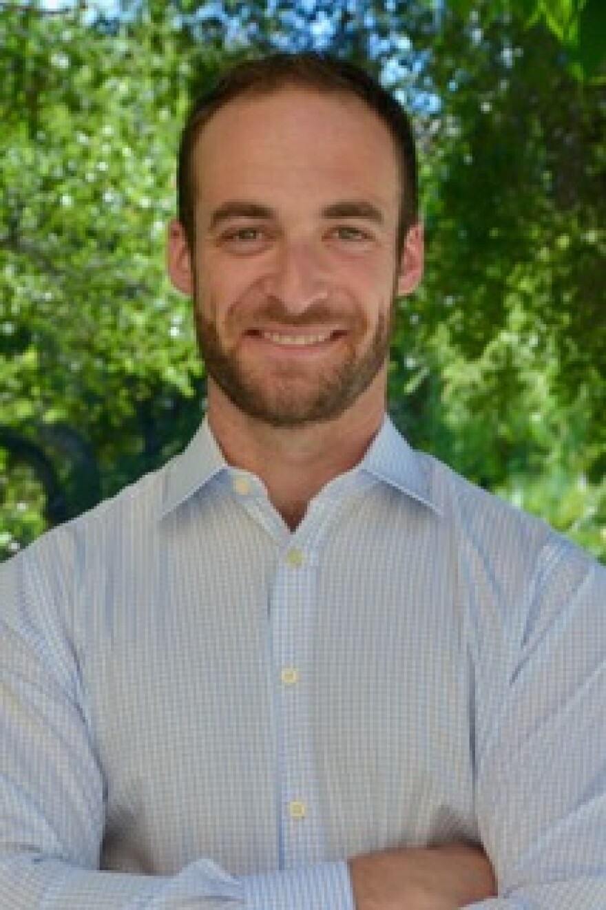 Closeup of a man in a collared shirt and sporting a beard.