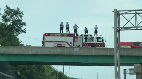 Bloomington fire fighters stand on an overpass of Ind. 45/46 Wednesday for the funeral procession of Owen County EMT Brandon Staley.