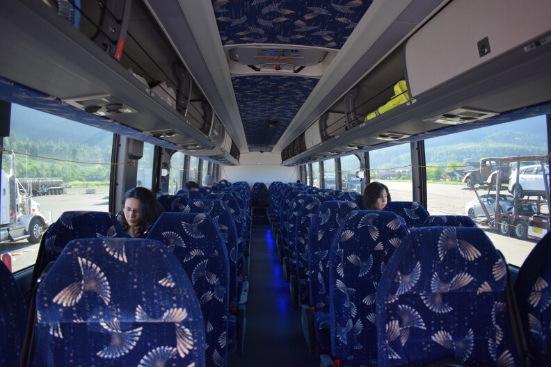 Commuters sit on a bus as it waits in a parking lot.