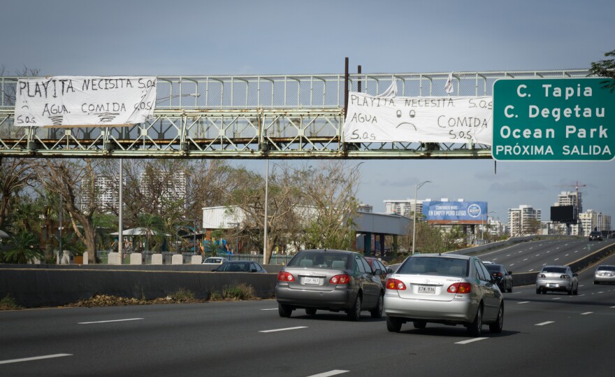 A pair of SOS signs hang from a pedestrian overpass in the San Juan's Playita neighborhood asking for food and water following Hurricane Maria's destruction in Puerto Rico.