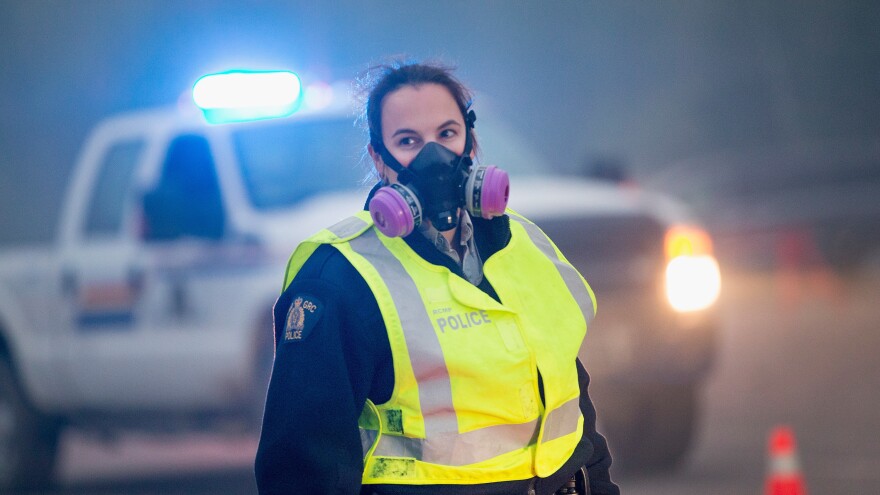 Smoke fills the air as a police officer stands guard at a roadblock along Highway 63 leading into Fort McMurray on Sunday.