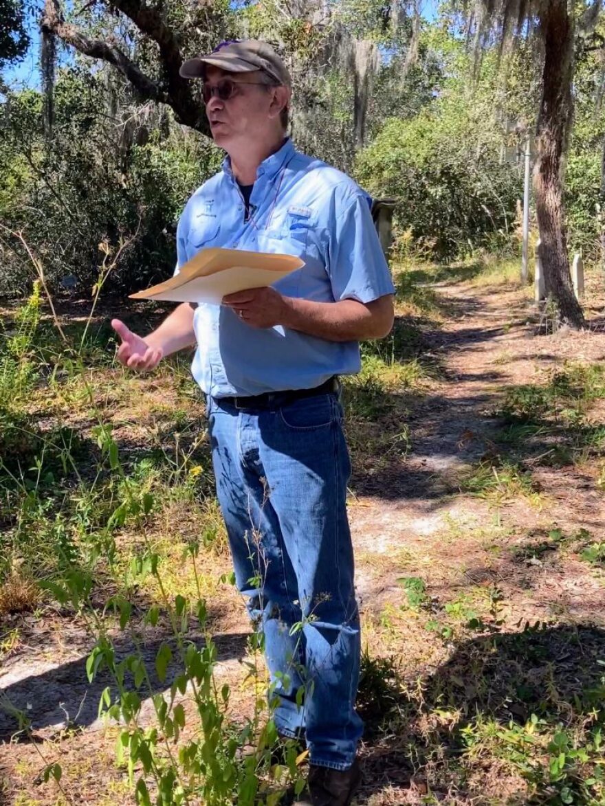 Man holding a folder and standing in woods