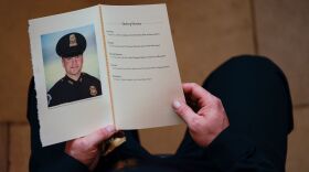A U.S. Capitol Police officer holds a program during a Feb. 3 ceremony honoring Brian Sicknick in the Capitol Rotunda. A medical examiner determined that Sicknick died of natural causes following the Jan. 6 insurrection.
