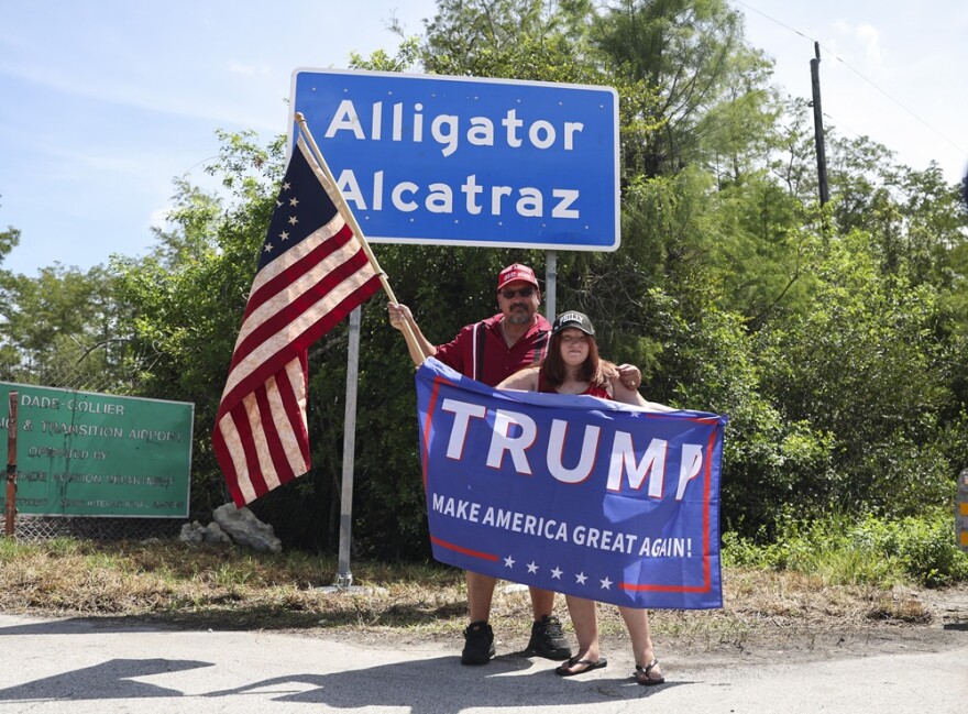 David Mourer and Rana Mourer pose for a photo in front of a sign reading "Alligator Alcatraz" outside the Dade-Collier Training and Transition Facility, Saturday, July 12, 2025, in Ochopee, Fla.